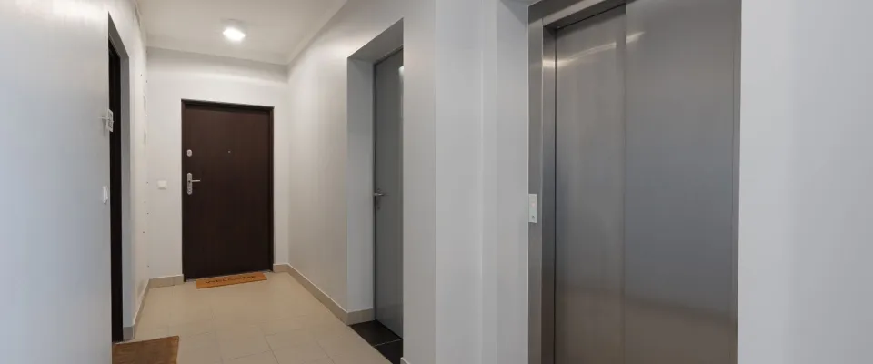 Clean, well-lit apartment hallway with a secure front door and elevator, illustrating the importance of spring break safety when choosing rental accommodations.