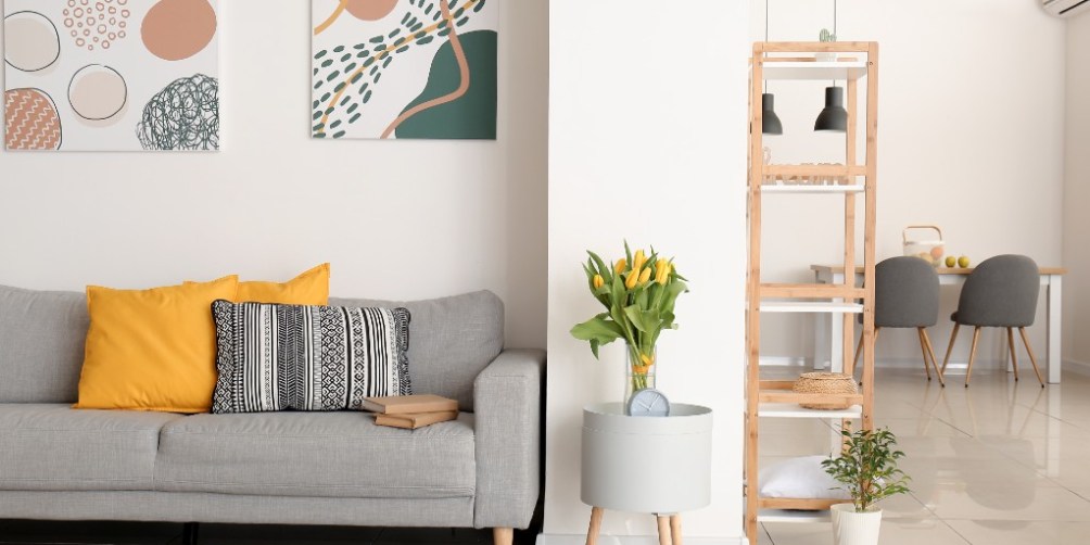 Bright and modern apartment living room with yellow tulips, geometric wall art, and minimalist decor, illustrating examples of renter-friendly spring home improvements.