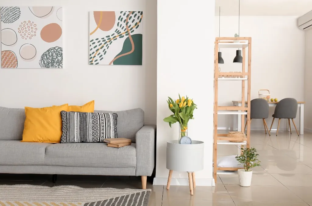 Bright and modern apartment living room with yellow tulips, geometric wall art, and minimalist decor, illustrating examples of renter-friendly spring home improvements.