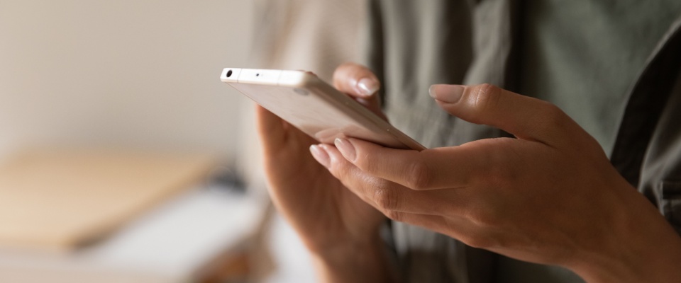 Hands holding a smartphone, illustrating the process to transfer renters insurance by contacting your insurance provider to update your policy details when moving to a new address.