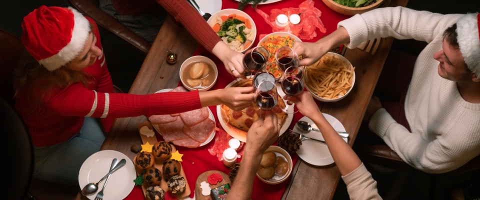 Group of friends raising glasses at a holiday dinner table, highlighting the importance of holiday safety during gatherings and celebrations.