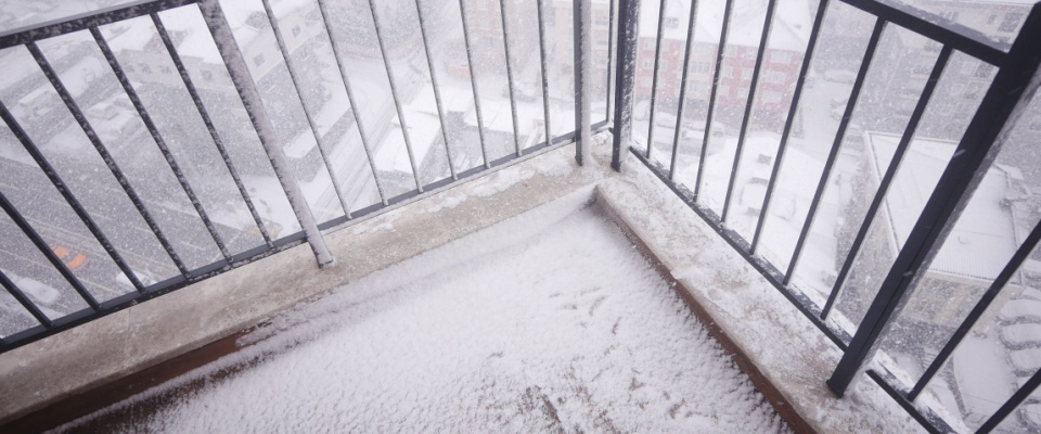 Snow-covered apartment balcony and railing after a winter storm, highlighting snow shoveling safety considerations for icy residential areas.
