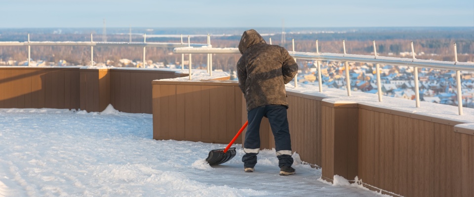 Person carefully removing snow from a rooftop area, emphasizing snow shoveling safety and proper responsibility in multi-unit buildings.
