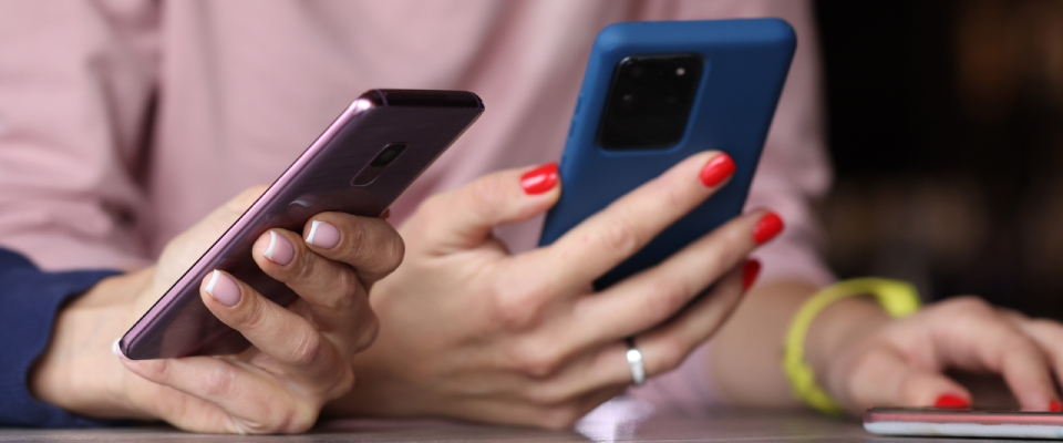 Two people comparing options on smartphones while researching whether to renew lease or move.