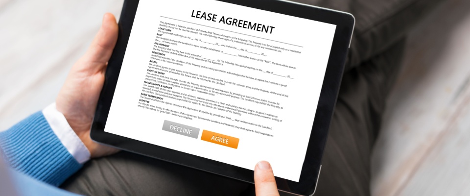 Person holding a tablet displaying a digital lease agreement, reading it carefully in order to ask any relevant questions before signing it.