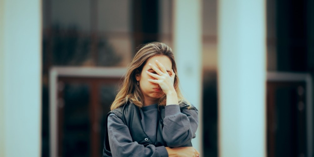 Woman standing outdoors with arms crossed, wearing a gray sweatshirt, visually representing renters insurance mistakes such as overlooking coverage details, underestimating personal property value, or not fully understanding policy exclusions and limitations.