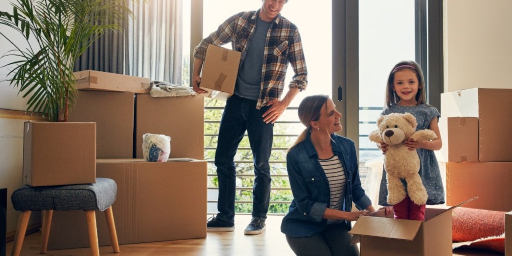 Young family packing boxes in their apartment during a move, illustrating the question: does renters insurance cover moving?