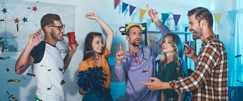 Group of friends dancing and celebrating together indoors, capturing the fun atmosphere of hosting a New Year’s Eve party at home.