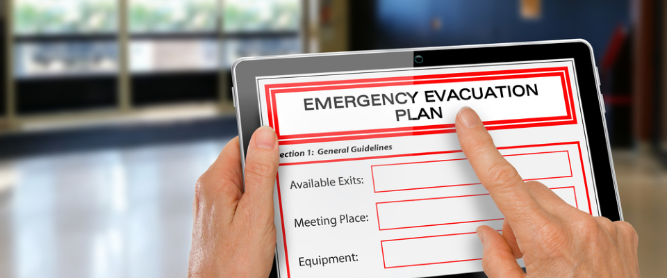 Person reviewing an emergency evacuation plan on a tablet, an important step in learning how to stay safe during a hurricane.