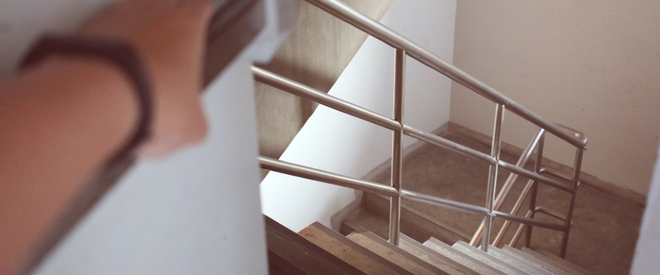 Person heading down an apartment stairwell during an evacuation, illustrating how to stay safe during a hurricane by knowing your exit route.