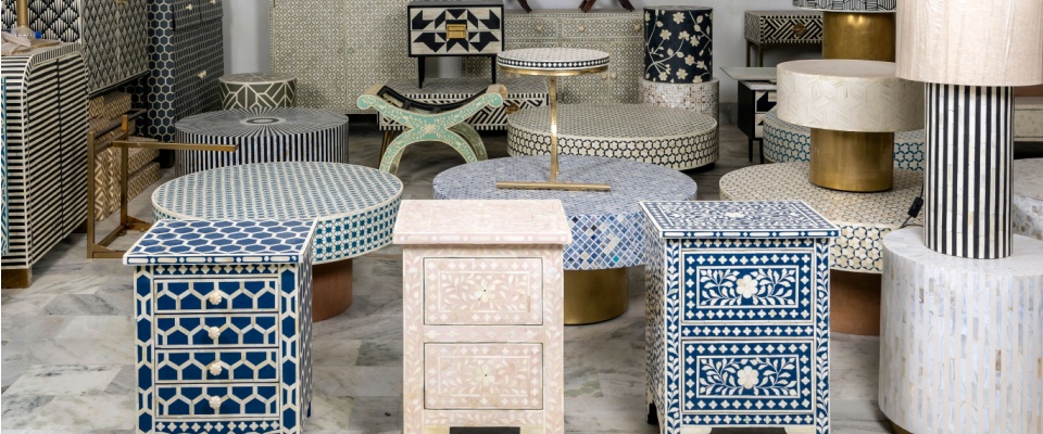 Display of intricately crafted side tables and stools with detailed patterns, highlighting interior design trends that emphasize craftsmanship and artisanal details.
