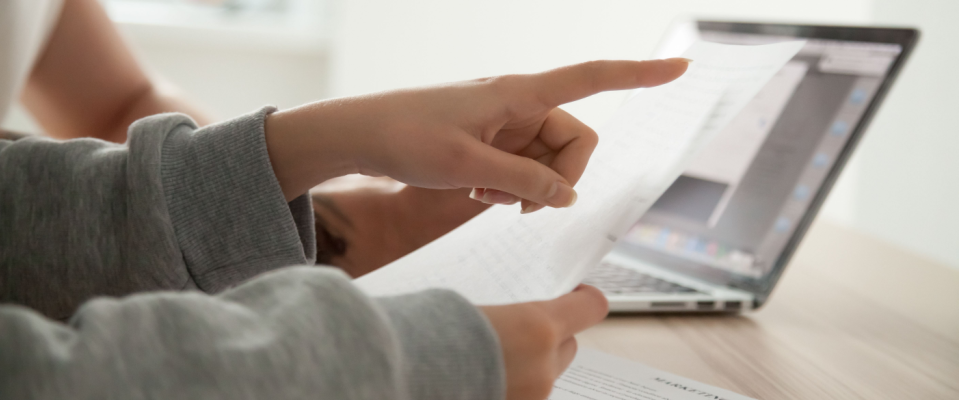 Two renters reviewing a document outlining the terms of renters insurance required by the landlord for their apartment, while sitting at a desk with a laptop.