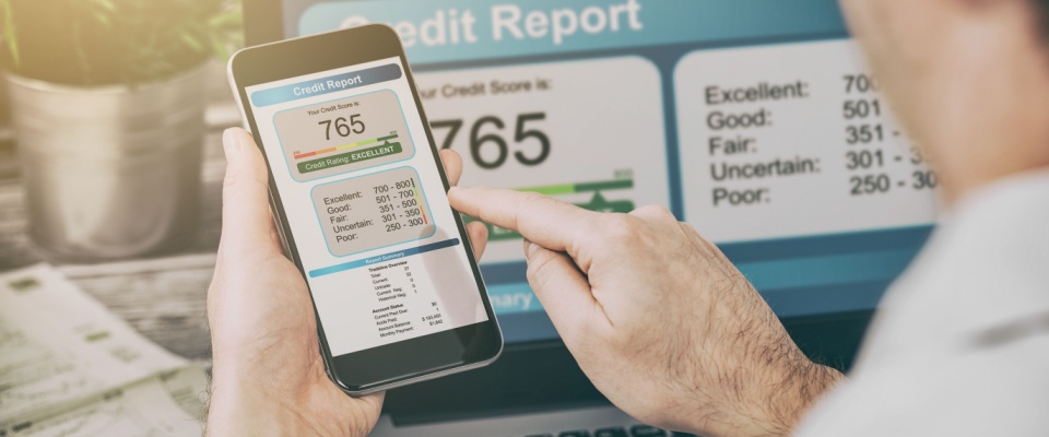 A person reviewing their credit score of 765 on a smartphone and laptop, while the question of "does renters insurance affect credit score?" might be on their mind.