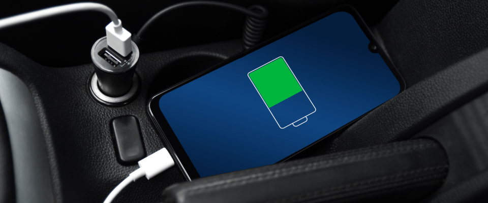 Smartphone charging in a car with a USB adapter, showing that renters insurance doesn't cover vehicle damage, but it can cover stolen electronics left in a car.