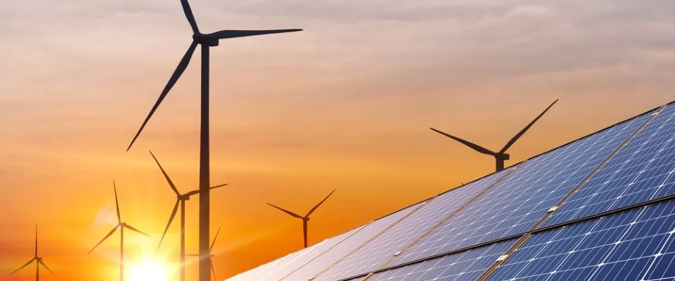 Rows of solar panels and wind turbines at sunset, showcasing the importance of renewable resources over nonrenewable ones.