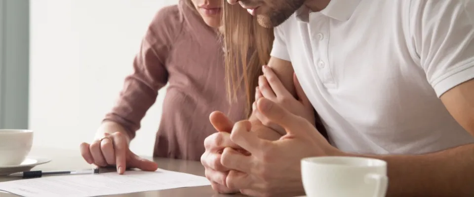 Couple sitting at a table closely reviewing a lease agreement, illustrating how to break a lease and negotiate terms for an exit agreement.