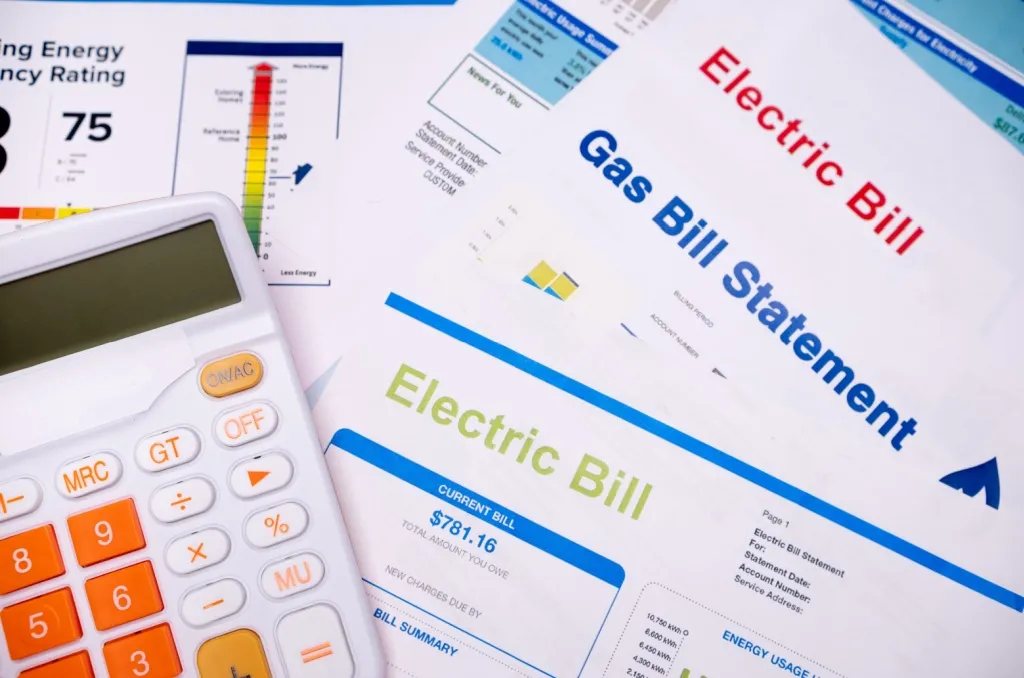 Calculator on top of electricity and gas bills, visually representing the convenience of all-bills-paid-apartments, where utilities are included in the monthly rent.