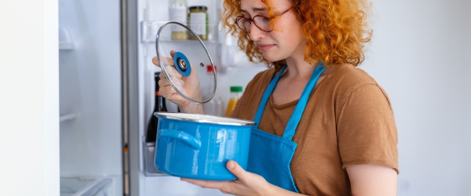 Woman inspecting food in a refrigerator after a blackout to ensure safety and reduce waste when the power goes out.
