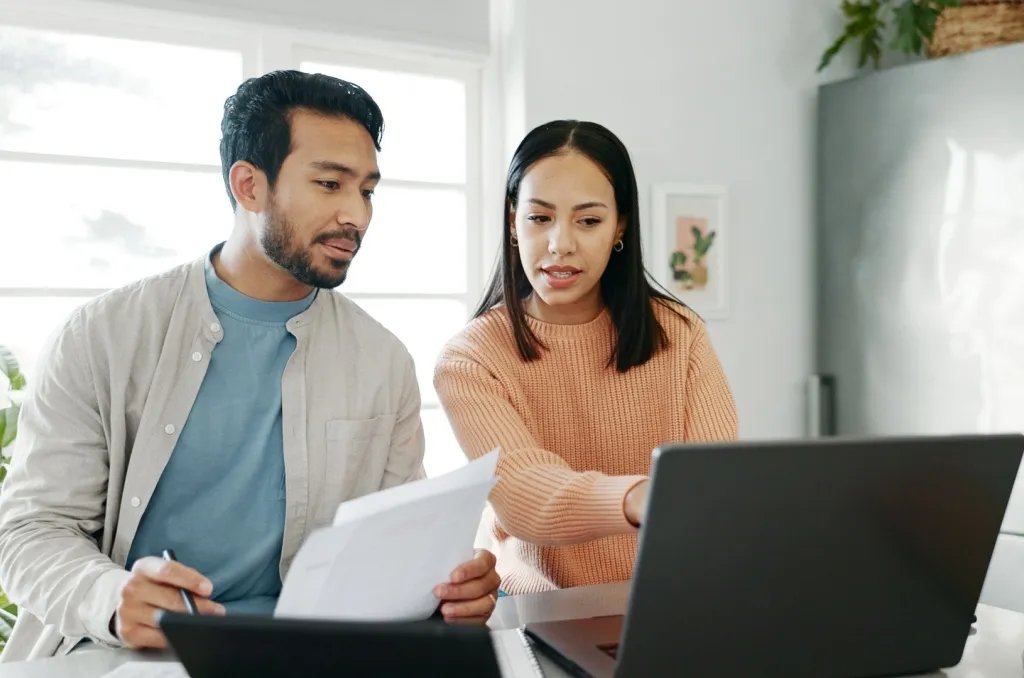 Couple reviewing rental documents on a laptop, researching how breaking a lease could hurt their credit score.