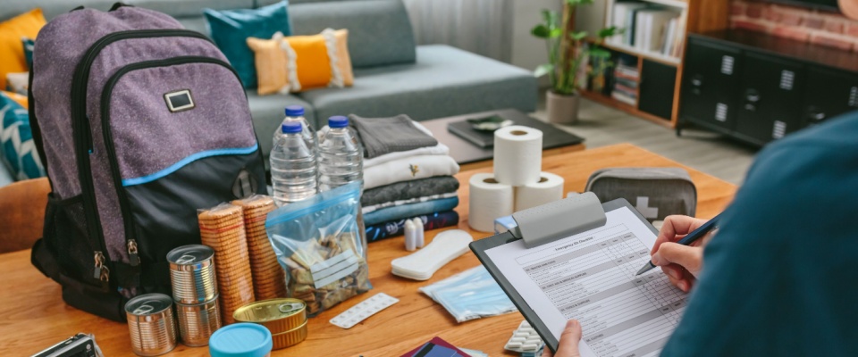 Emergency kit with water, canned food, supplies, and checklist laid out on a table, showing essential backup power for your apartment during outages.