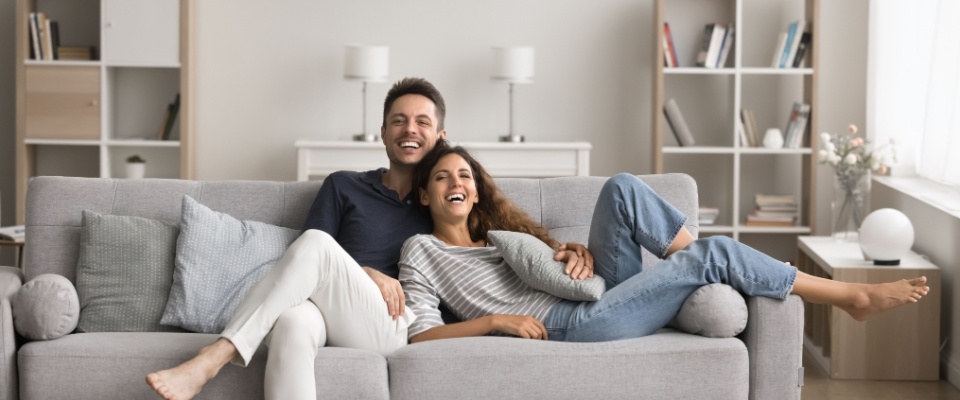 Couple relaxing comfortably on a couch in their living room, highlighting lifestyle considerations when choosing homeowners versus renters insurance.