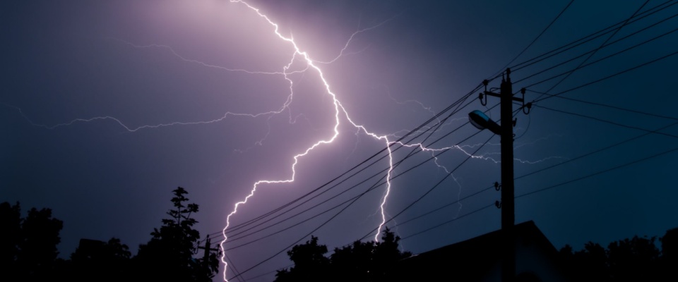 Lightning storm hitting electrical lines, highlighting outage repairs and maintenance expenses included in TDU delivery charges.