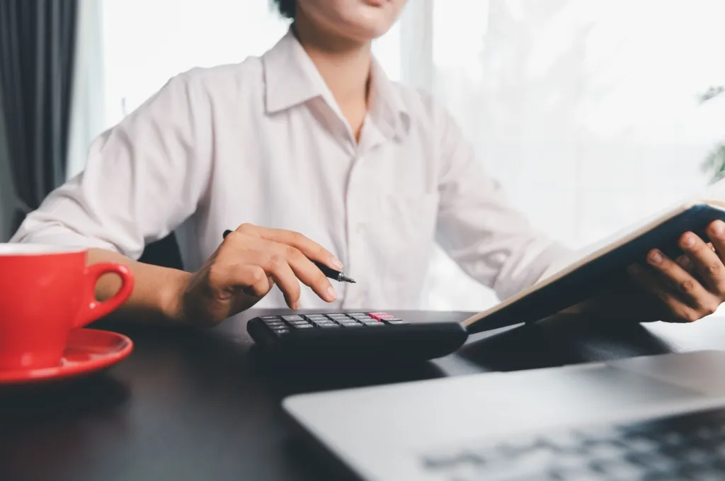 Individual calculating expenses at a desk with calculator and documents while evaluating whether renters insurance is tax deductible on a federal tax return.