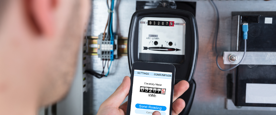 Man using a smartphone app to record a 032075 kWh reading from an electric meter, demonstrating how to read an electric meter and track energy usage digitally.