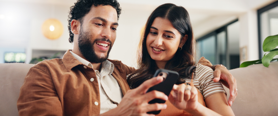 Couple reviewing renters insurance policy options on a smartphone together, illustrating renter safety tips for protecting belongings.