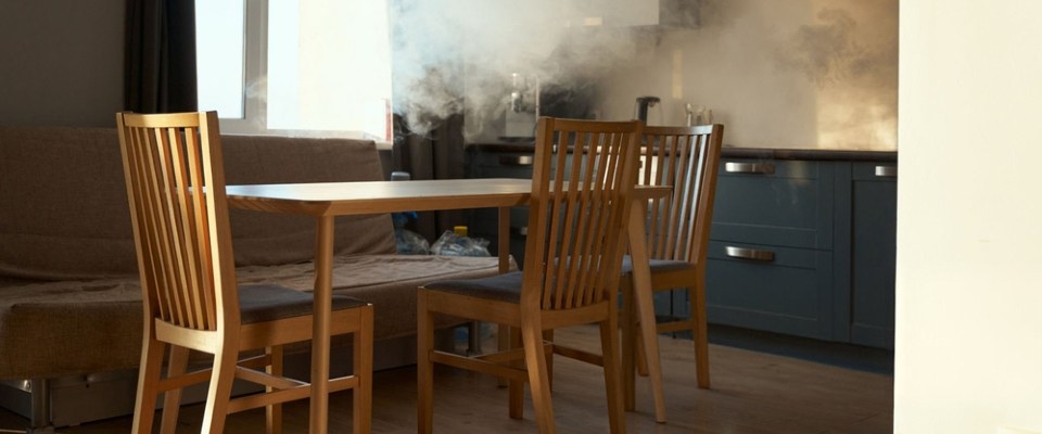 Smoke filling an apartment kitchen and dining area, showing a fire hazard covered by renters insurance in Michigan.